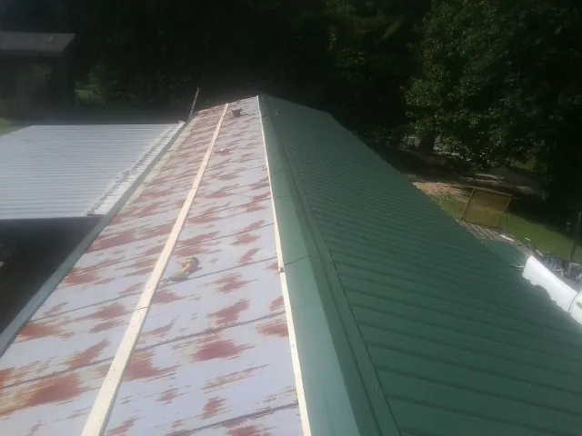 Old rusted panels beside newly installed green metal roofing — Wind Damage Roof Repair by Roofing Brothers in Meherrin