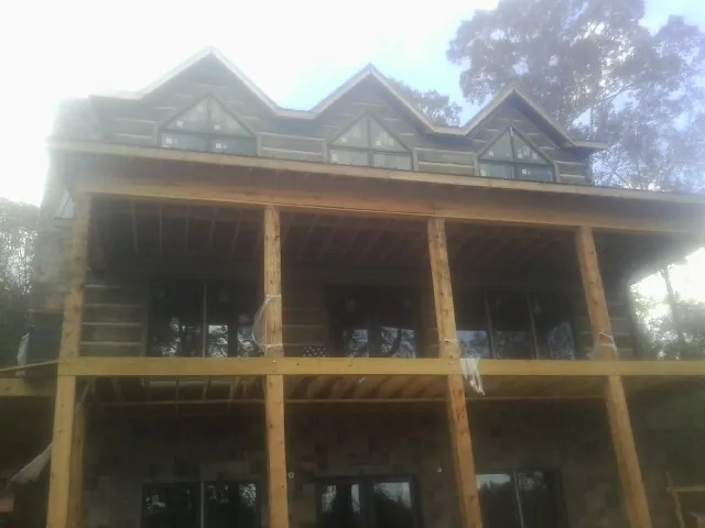 Dormers and porch framing on a large log home under construction — Roof Coating work by our crew in Meherrin