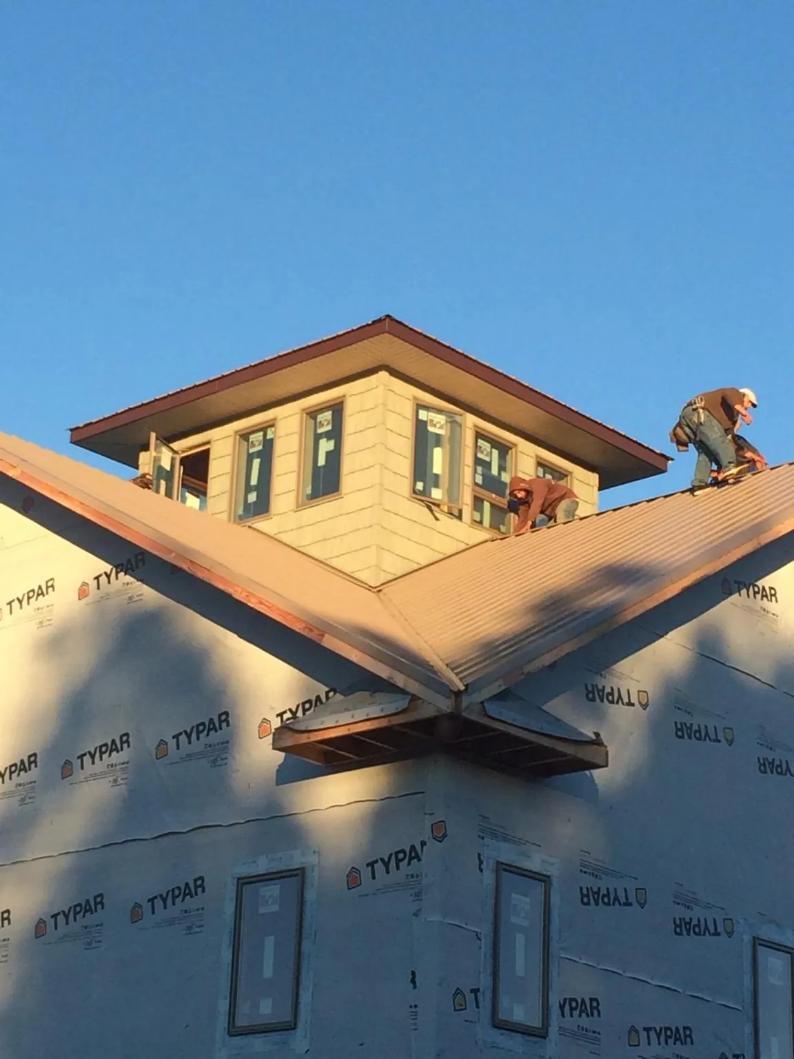 Roofers working around a rooftop cupola on a new metal roof at sunset — Roof Waterproofing in Meherrin by Roofing Brothers